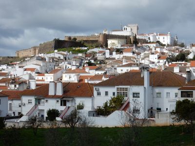 A final view of Estremoz; rows of white houses with red roofs, climbing to the base of the castle walls at the top of the hill.