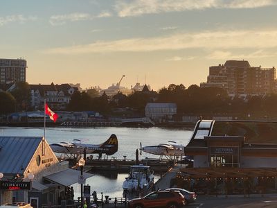 skyline across Inner Harbour, Victoria, with a massive modern cruise ship on the horizon, dwarfing the surrounding buildings.