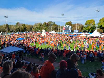 the powwow circle full of people, some in regalia but most in orange t-shirts, dancing and intertribal round dance