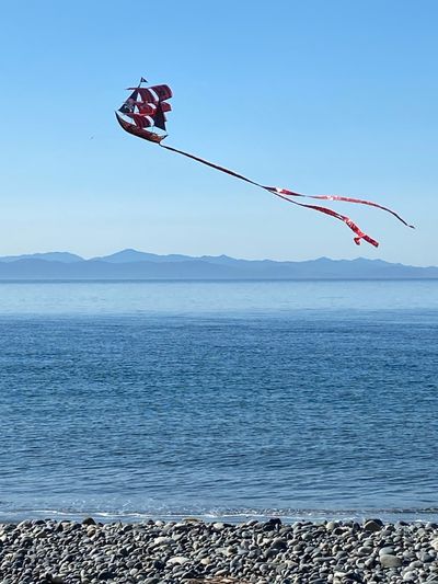 a kite in the shape of a pirate ship with the Olympic Mountains in the background, French Beach