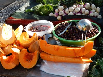 a market stall featuring long, orange sections of winter squash.