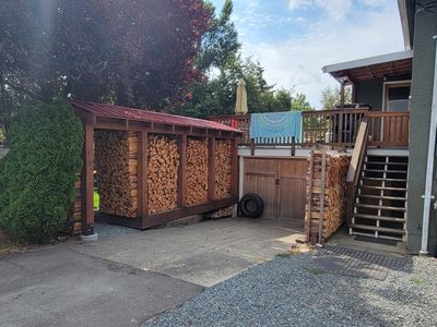 A neatly stacked, covered wood shed beside a house in Oaklands, Victoria BC