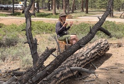 Joan conducting the podcast chat on a log while on a hike