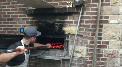 Bryn Rawlyk moving coals in his brick oven
