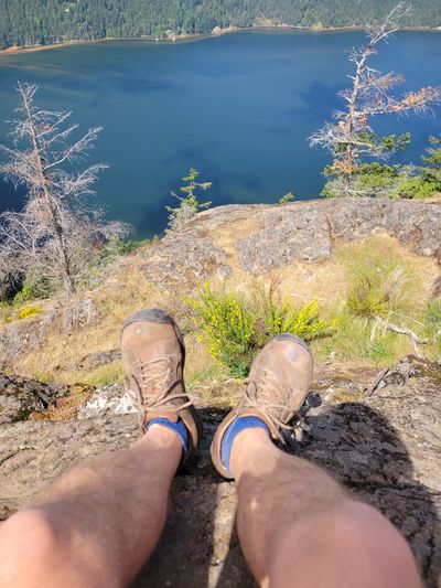 Mark's legs dangling over a rock ledge on Jocelyn Hill