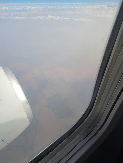 a photo out the airplane window, showing grainfields below, but masked with a thick, brown haze from forest fire smoke